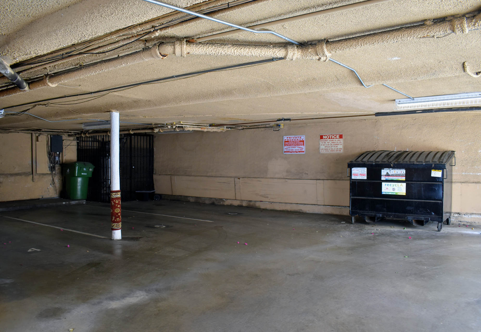 the inside of a parking garage with bins and a pole